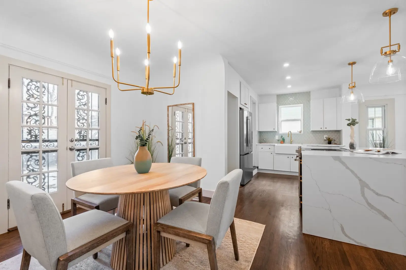 Dining room opening to a white kitchen in a brick Tudor