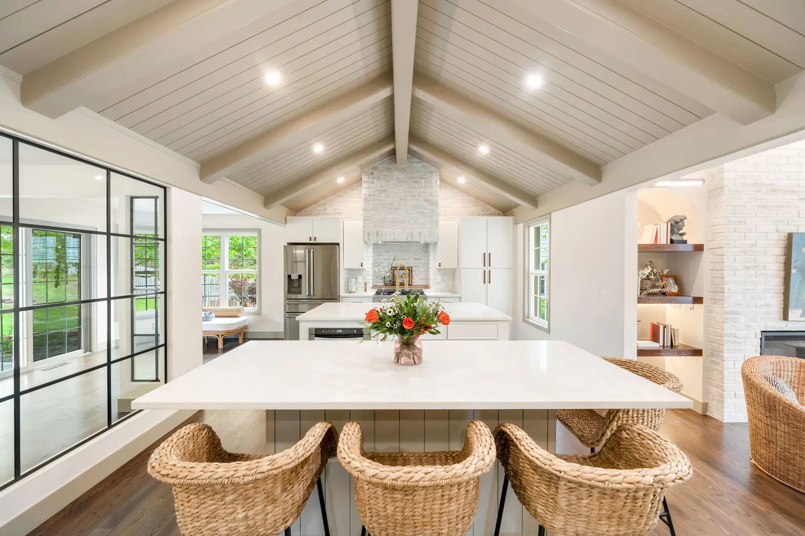 Vaulted white kitchen with an island and wood range hood